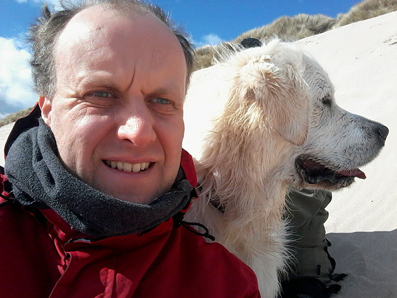 David and his golden retriever on a white sand background