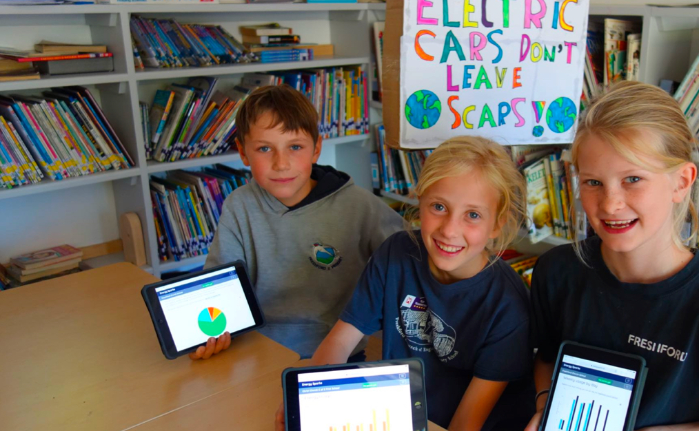 Children sat at a table showing the energy sparks app on their tablet devices.