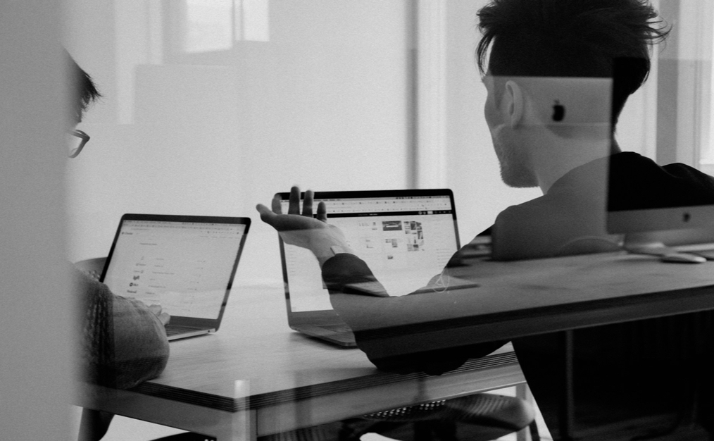 Black and white photo of two people sat at laptops