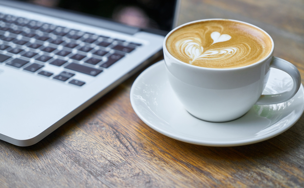 Cup of coffee next to a laptop